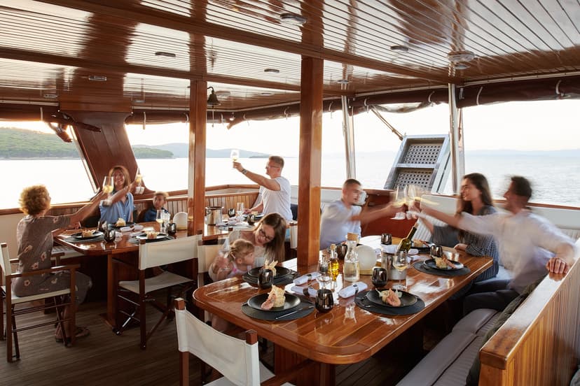 Group toasting with wine glasses on a wooden boat deck overlooking the sea and islands
