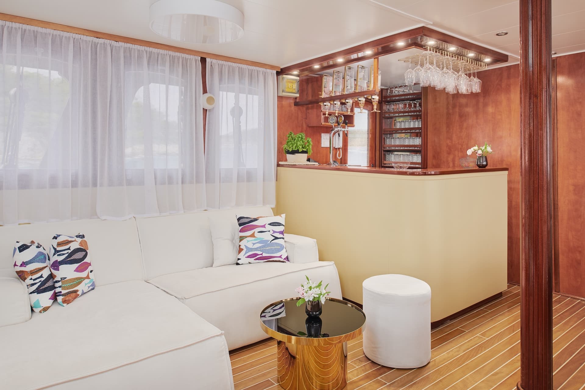 Interior lounge area with white couch, bar, and wood paneling on a boat.