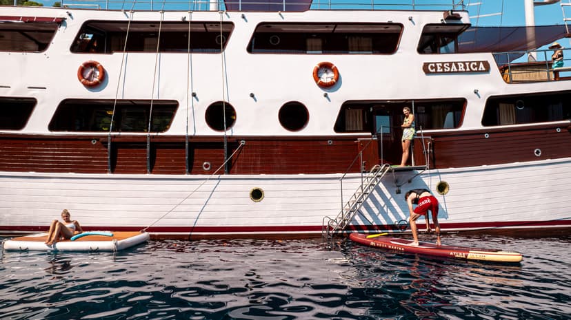 People enjoying water activities next to the yacht named Cesarica with Sibenik life preserver.