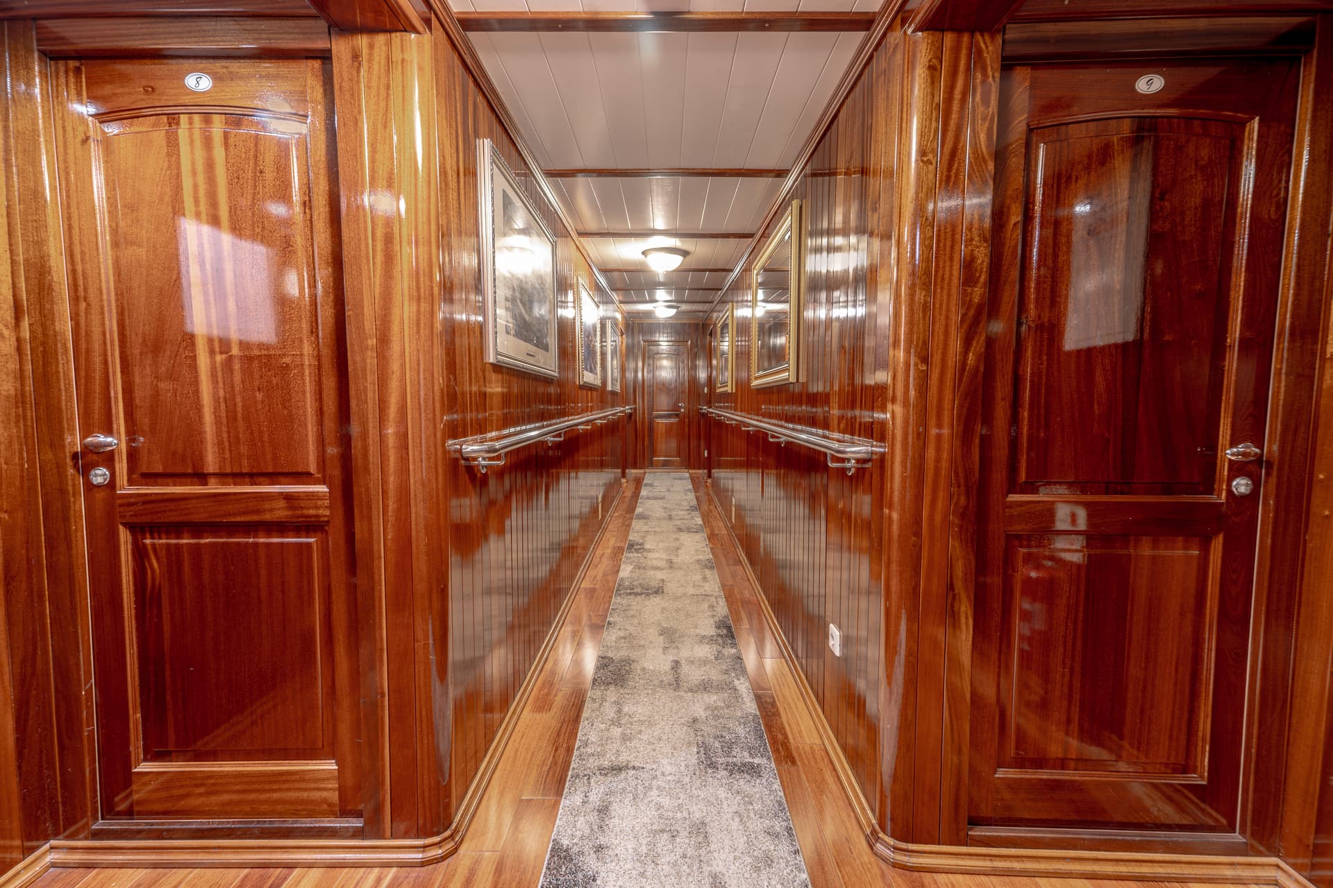 Hallway with glossy wood paneling, doors numbered 8 and 9, and a long metal handrail.