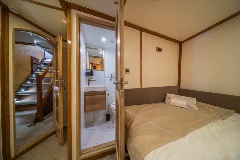 Cabin bedroom with view of illuminated stairs and small ensuite bathroom