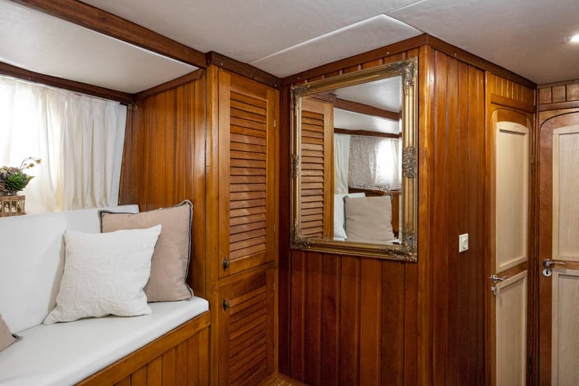 Cabin interior with rich wood paneling, white seating, and ornate gold-framed mirror