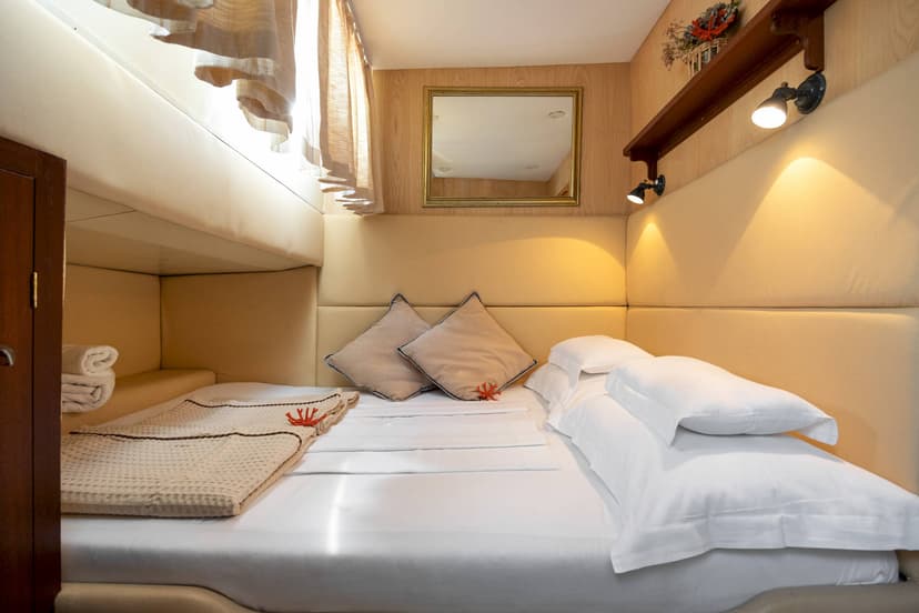 Cozy cabin bedroom with bunk and double bed, padded walls, and warm lighting.