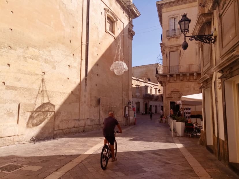 Lecci, Italy. Sunrise in old town. Play of light and shadow. Sityscape with bicycling man.