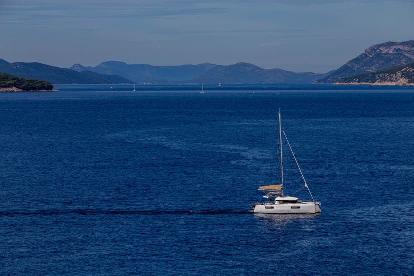 yacht cruises on the Adriatic Sea in the region of Dubrovnik, Croatia, with islands in the background, sunny day, clear weather, intense blue.