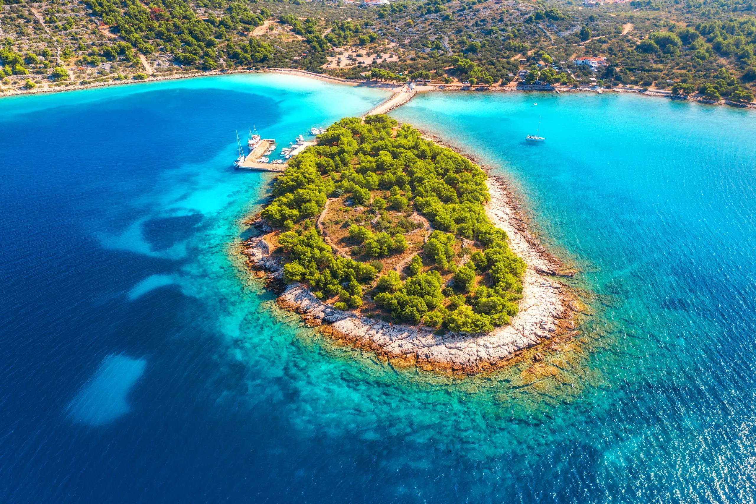 Luchtfoto van mooi klein eiland in zeebaai op zonnige dag in de zomer in Murter, Kroatië. Bovenaanzicht van transparant blauw water, groene bomen, berg, zandstrand, boten en jachten. Tropisch landschap