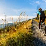 Mountain biking woman riding on bike in summer mountains forest landscape. Woman cycling MTB flow trail track. Outdoor sport activity.